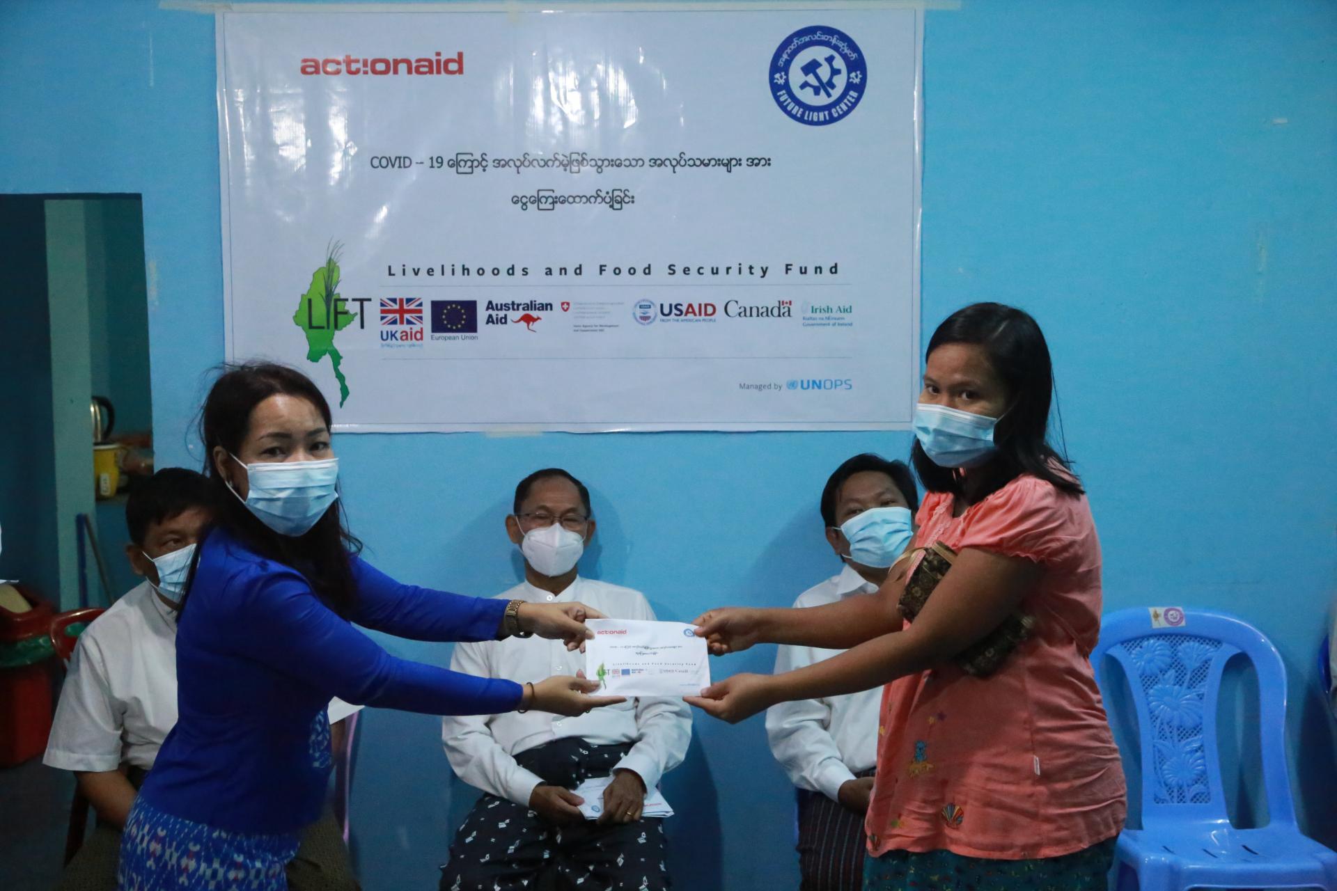 Thet Thet Aung, Director of the Future Light Center, ActionAid’s partner, presents cash support to a pregnant factory worker. Photo | @Future Light Centre